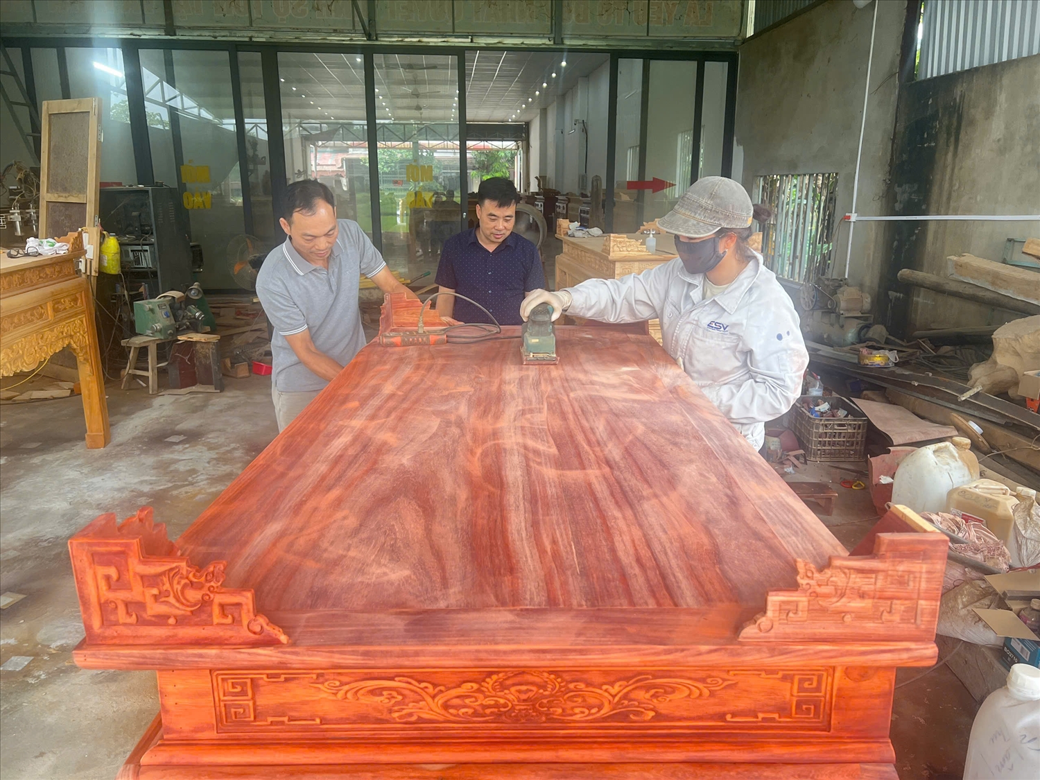 Anh Minh Hiếu (bên trái) cùng công nhân đánh bóng cho sản phẩm đồ thờ mỹ nghệ.