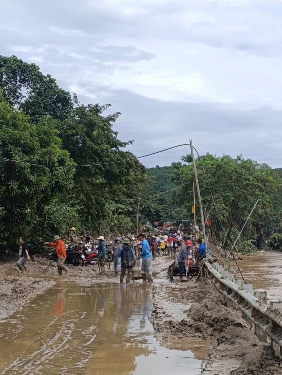 Xã Tam Quang chủ động huy động người dân các bản làng không bị ngập lũ, tham gia dọn dẹp bùn đất, thông tuyến quốc lộ 7 - Ảnh: Thanh Hải