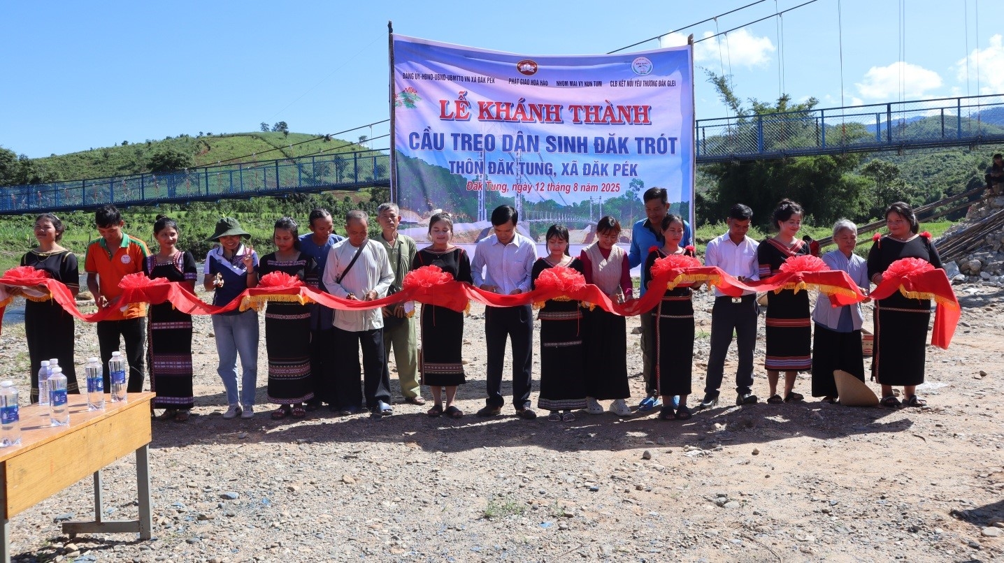 Lãnh đạo xã Đăk Pék và đại diện các nhóm thiện nguyện cắt băng khánh thành cầu treo dân sinh bắt qua suối Đăk Trót. (Ảnh: Ngọc Chí)
