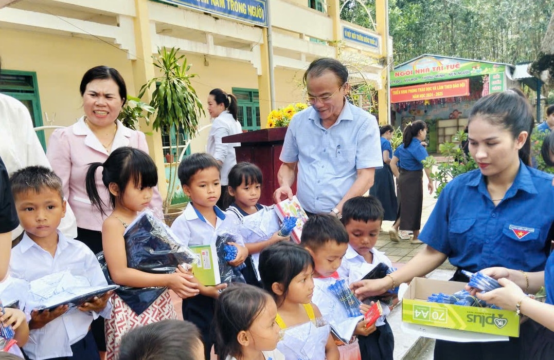 Ông Nguyễn Ngọc Thái (đứng giữa) - Giám đốc Sở Giáo dục & Đào tạo tỉnh Quảng Ngãi trao quà cho học sinh có hoàn cảnh khó khăn tại xã Trà Bồng và xã Cà Đam. (Ảnh: Ngọc Chí)