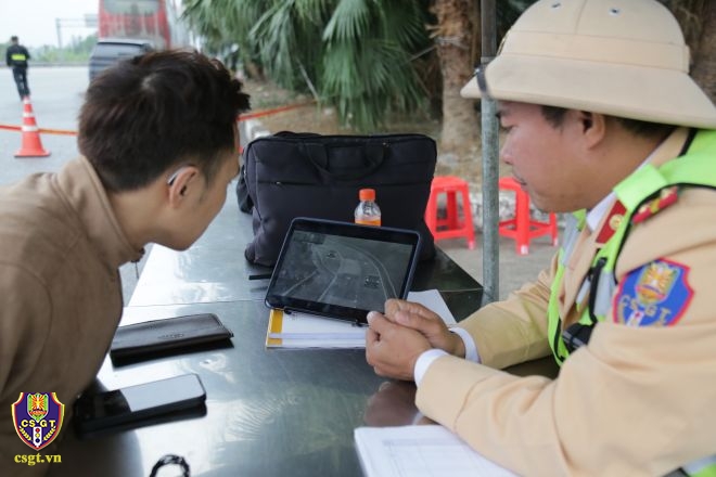 Cán bộ CSGT cho một tài xế xem lại hình ảnh vi phạm trên đường cao tốc Nội Bài - Lào Cai (Ảnh: Cục CSGT).