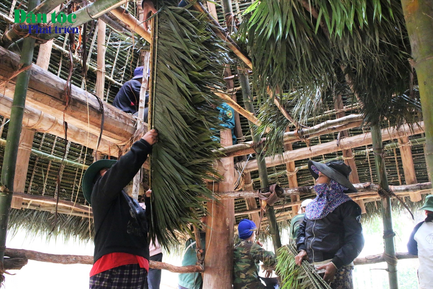 Phụ nữ trong làng phụ trách phần việc lấy lá mây và đan thành tấm để lợp mái nhà rông. (Ảnh: Ngọc Chí)
