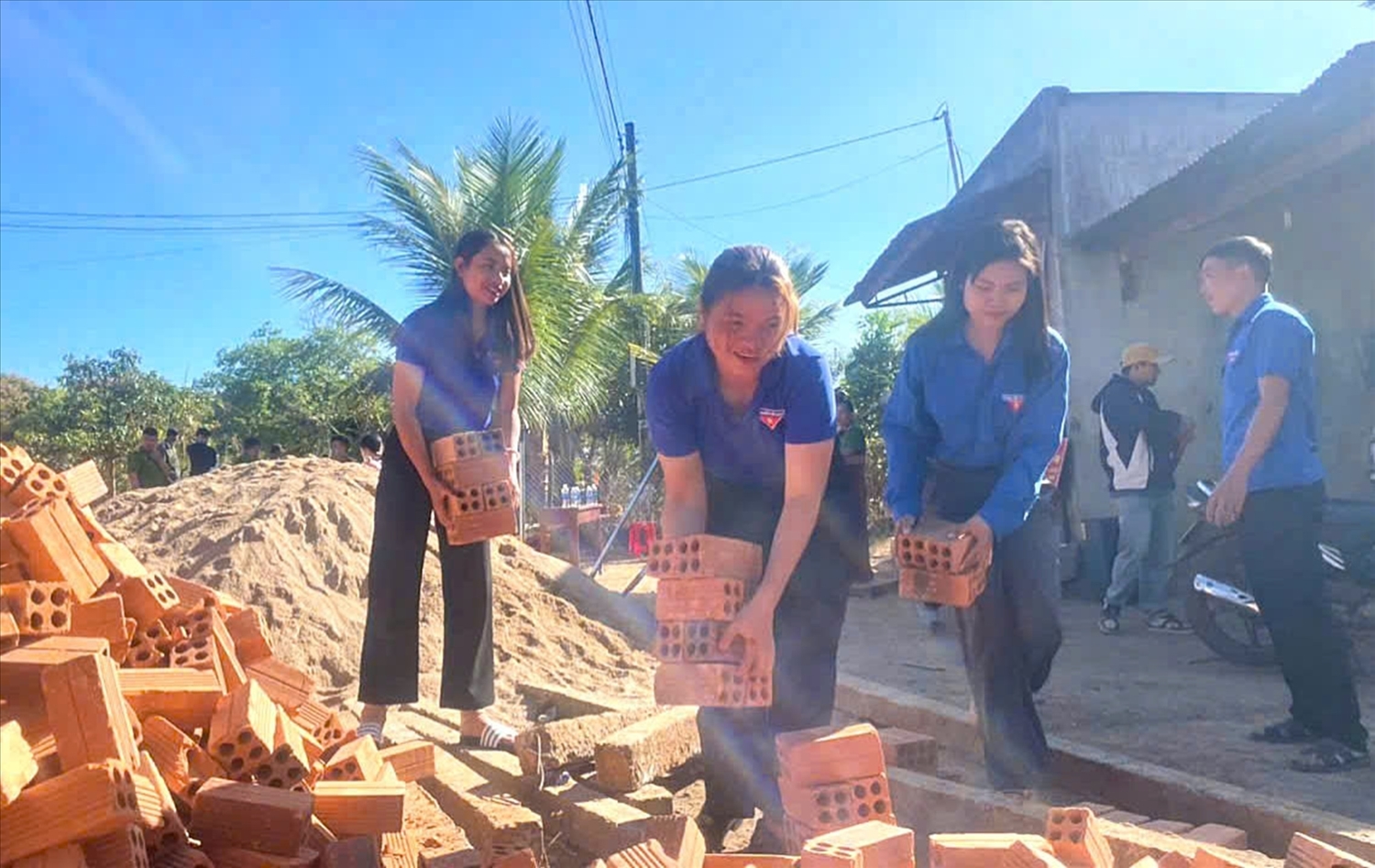Thanh niên tình nguyện xã Cư Pơng vận chuyển gạch giúp đội thợ đẩy nhanh tiến độ thi công (Ảnh: L.H)