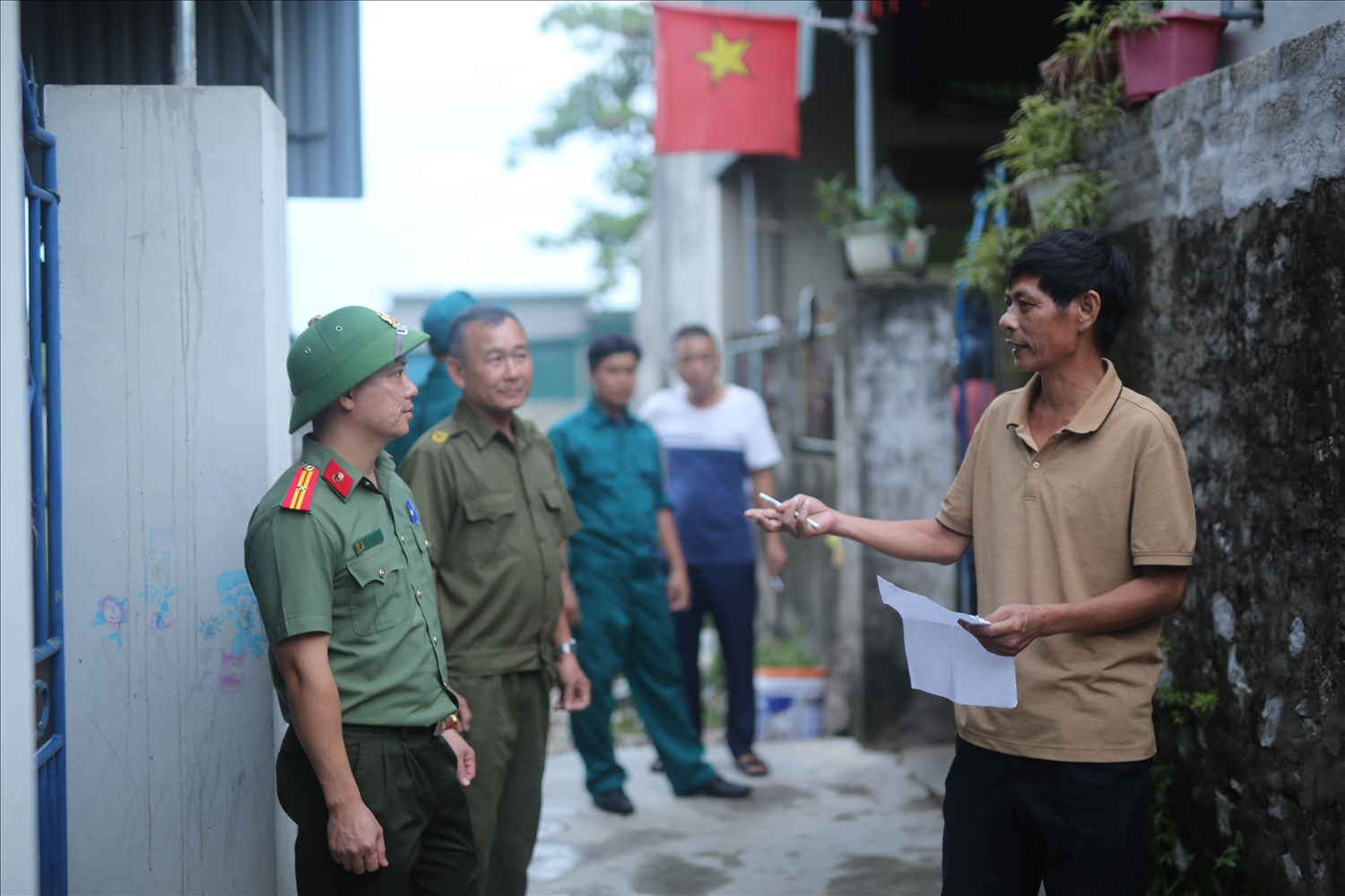 Xóm trưởng xóm Bắc Chiến Thắng, ông Nguyễn Cảnh Nam (bìa phải) trao đổi về kế hoạch vận động, sơ tán người dân với các lực lượng của xã Diễn Châu - Ảnh: Thanh Hải