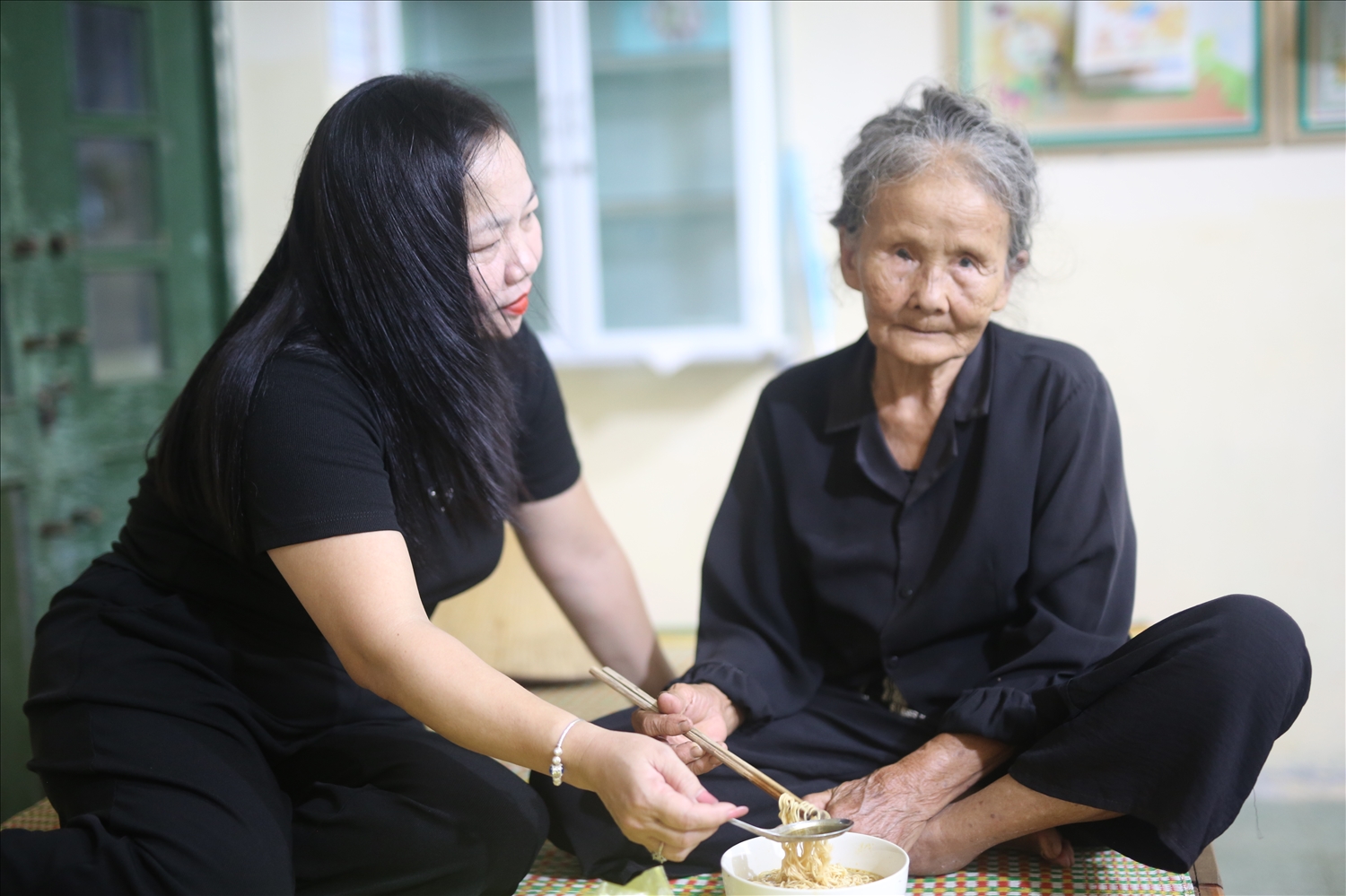 Bà Đậu Thị Tuyết ăn tạm mì tôm khi đã đến vị trí tránh trú bão số 5 tại trường Tiểu học Diễn Bích - Ảnh: Thanh Hải