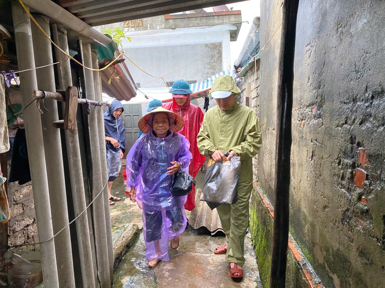Chính quyền xã Diễn Châu hỗ trợ bà Trần Thị Tân - vợ liệt sĩ, ở xóm Quyết Thắng di chuyển đến nơi an toàn - Ảnh: Thanh Hải