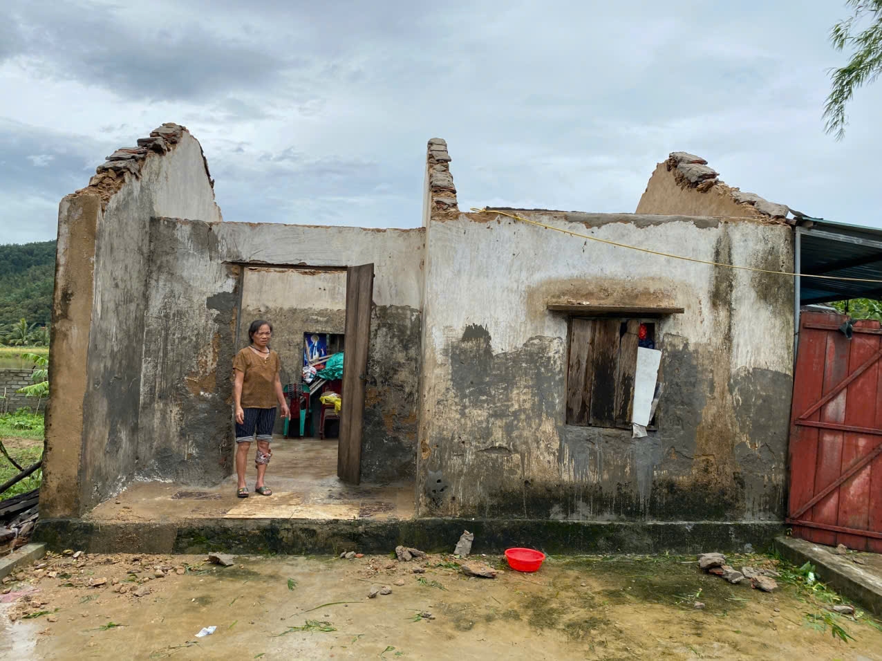 Bà Nguyễn Thị Thành, ở xóm 5, xã Trung Lộc trước căn nhà toang hoác do bão số 5 gây ra - Ảnh: Thanh Hải