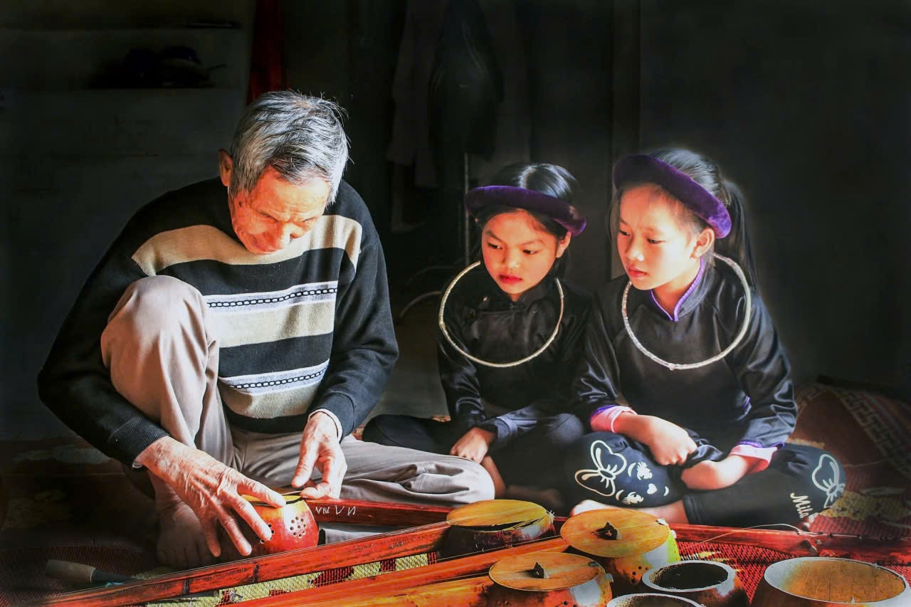 Nghệ nhân Ưu tú Lương Thiêm Phú đang truyền dạy, hướng dẫn trẻ em chế tác đàn tính (Ảnh: Mỹ Dung)