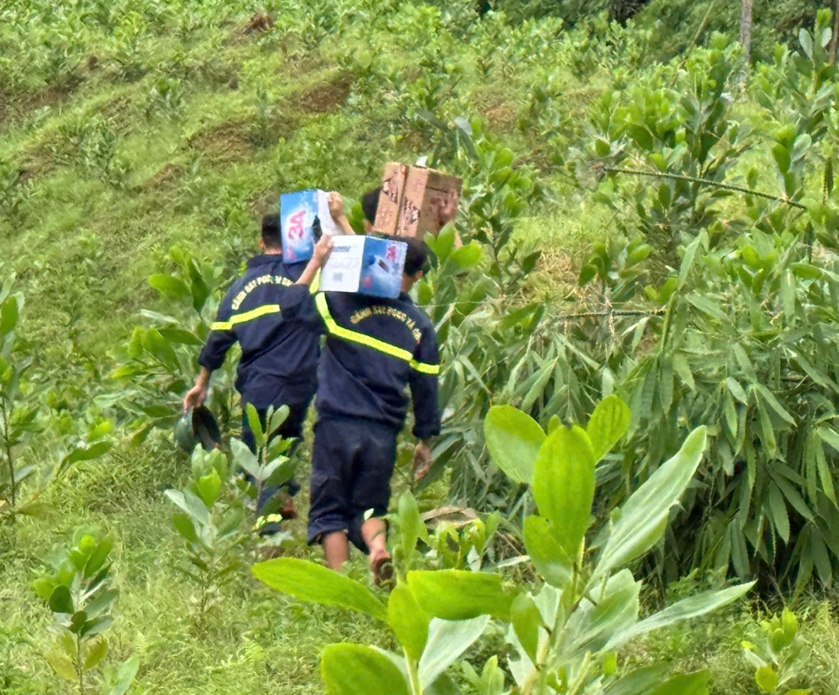 Cán bộ, chiến sĩ Công an vác nhu yếu phẩm xuyên rừng vào cứu trợ cho các hộ dân bị cô lập.(ảnh CTV)