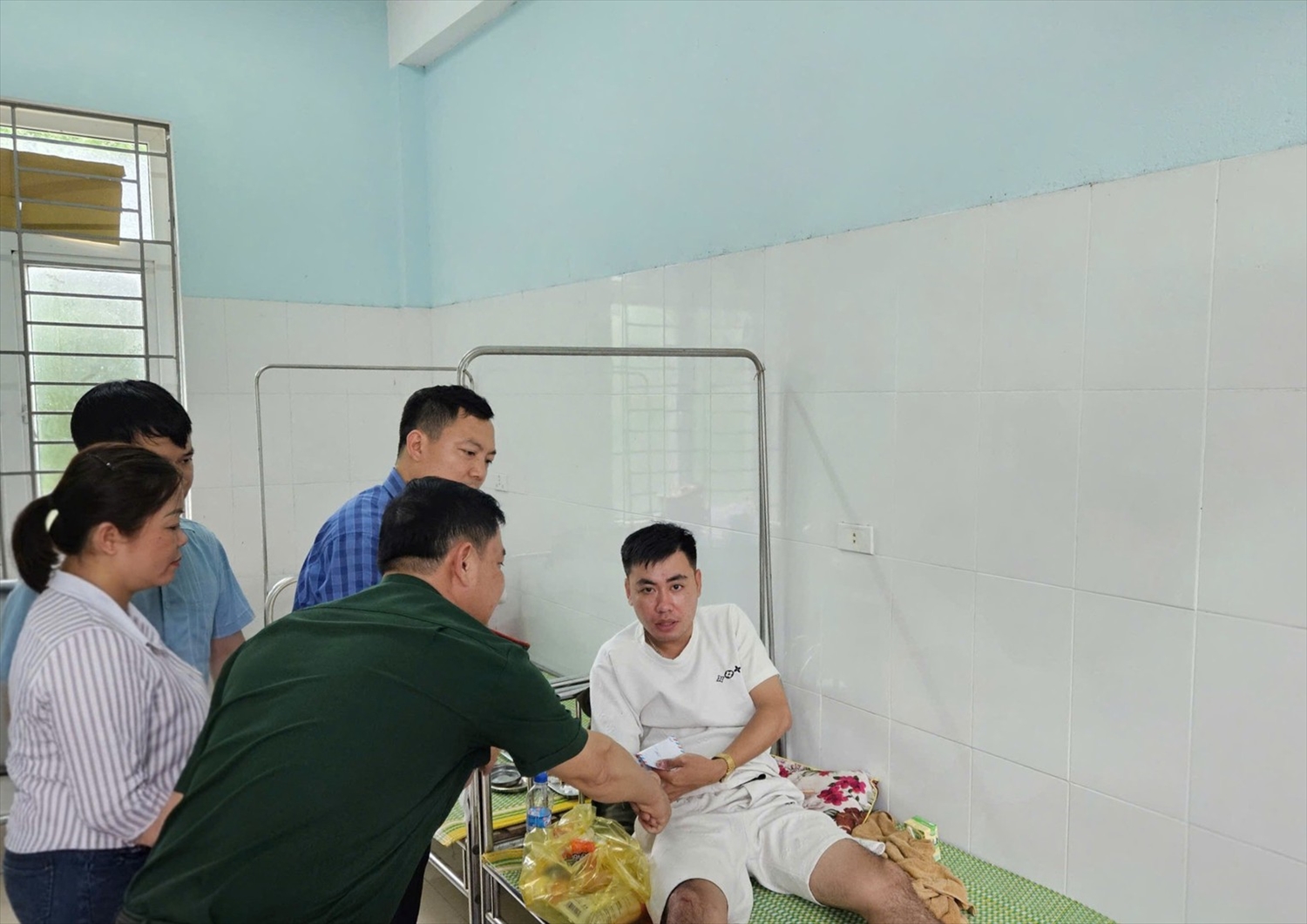 Nhân dân trên địa bàn xã Hiền Kiệt thăm hỏi, động viên Trung úy Lê Ngọc Vũ bị thương khi giúp dân phòng, chống bão số 5.(ảnh Thái Thanh)