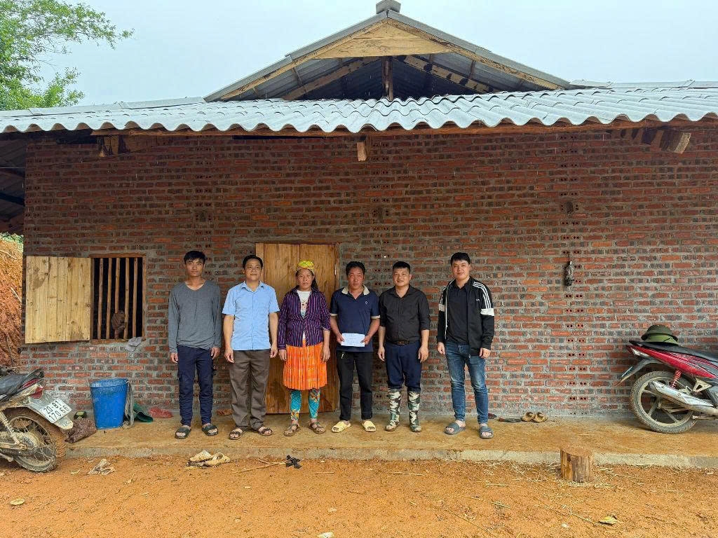 Anh Sùng A Sinh xóm Cao Bắc, xã Xuân Trường – Cao Bằng (thứ ba từ bên phải) bên ngôi nhà mới hoàn thành