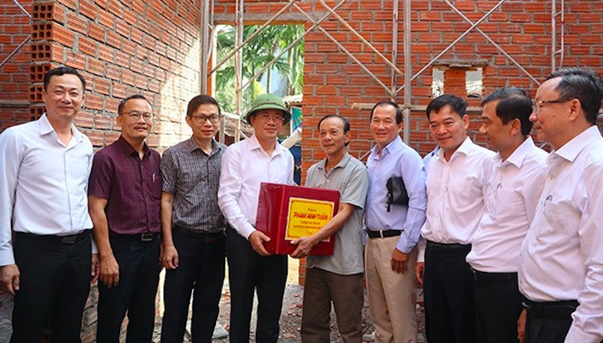 Ông Phạm Anh Tuấn, Chủ tịch UBND tỉnh Gia Lai (thứ 4 từ trái sang) tặng quà cho người dân có nhà mới tại xã An Lão , tỉnh Gia Lai (Ảnh T.Nhân)
