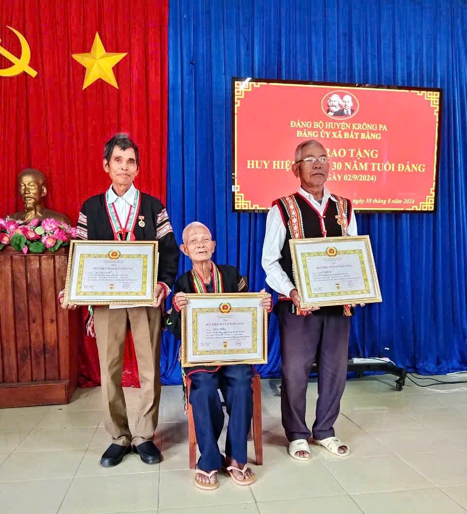 Già làng Ama Giai (ngồi giữa) nhận Huy hiệu 60 năm tuổi Đảng (Ảnh H.Quy)