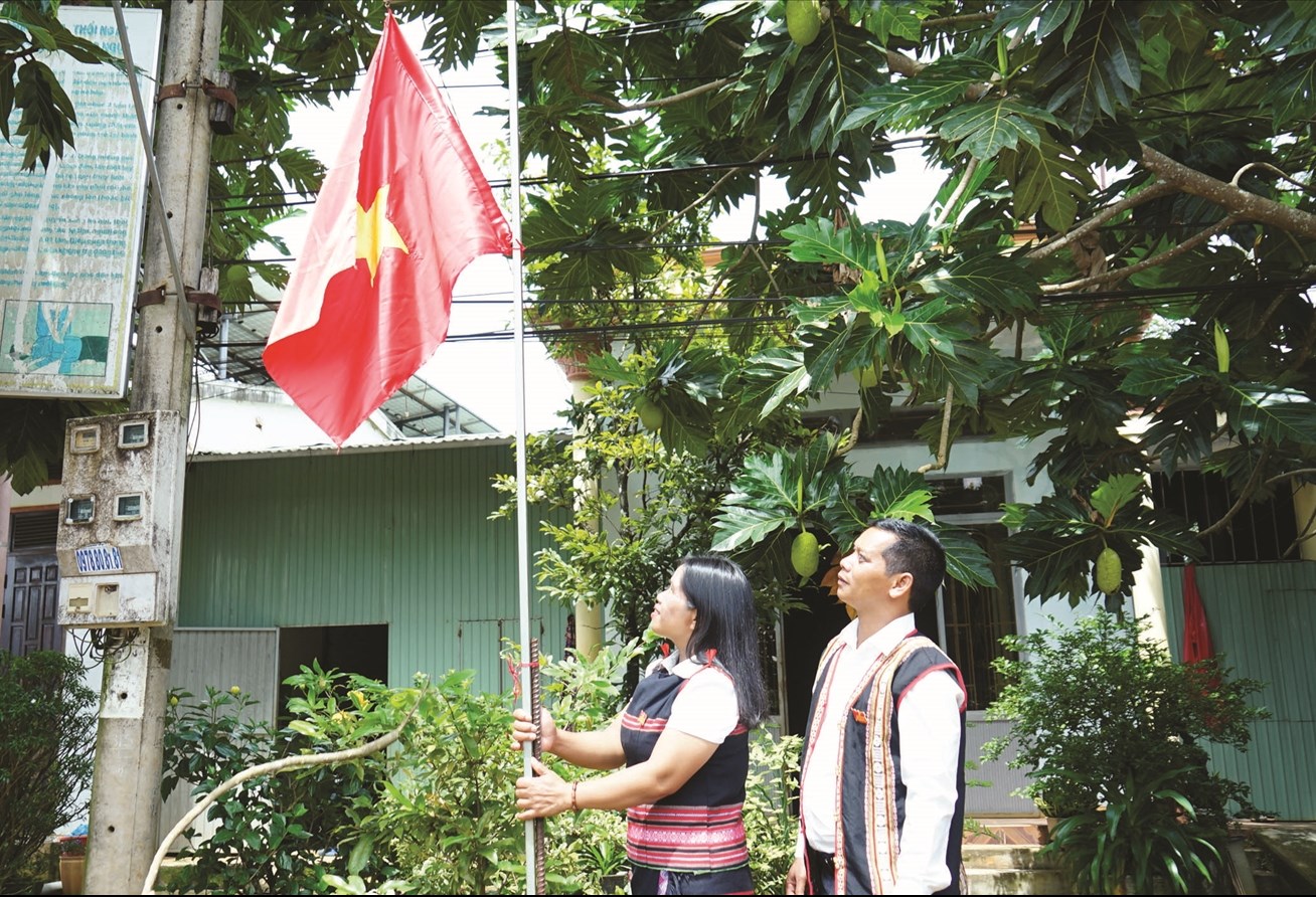 Chị Rơ châm Alui (làng Mông Yố 2) cùng dân làng treo cờ đỏ sao vàng trước nhà chào đón ngày Lễ lớn của đất nước