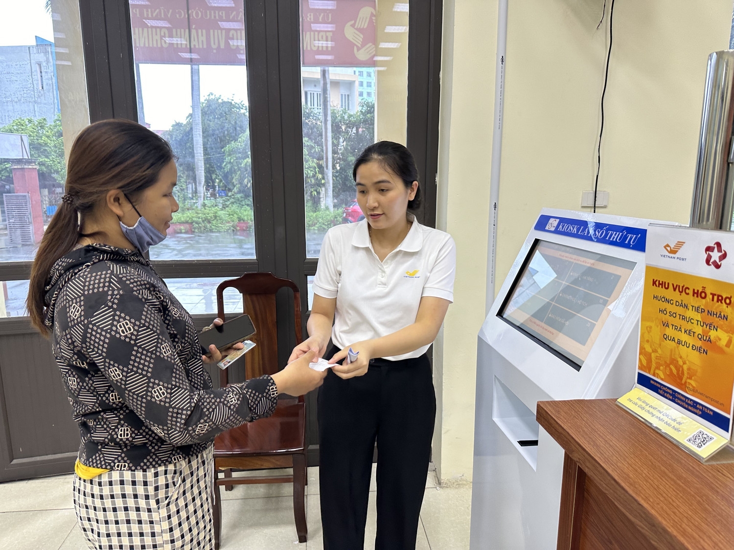 Cán bộ phường Vĩnh Phúc, tỉnh Phú Thọ hỗ trợ người dân đăng kí, lấy số khi làm thủ tục hành chính (Ảnh: Nguyễn Thảo).