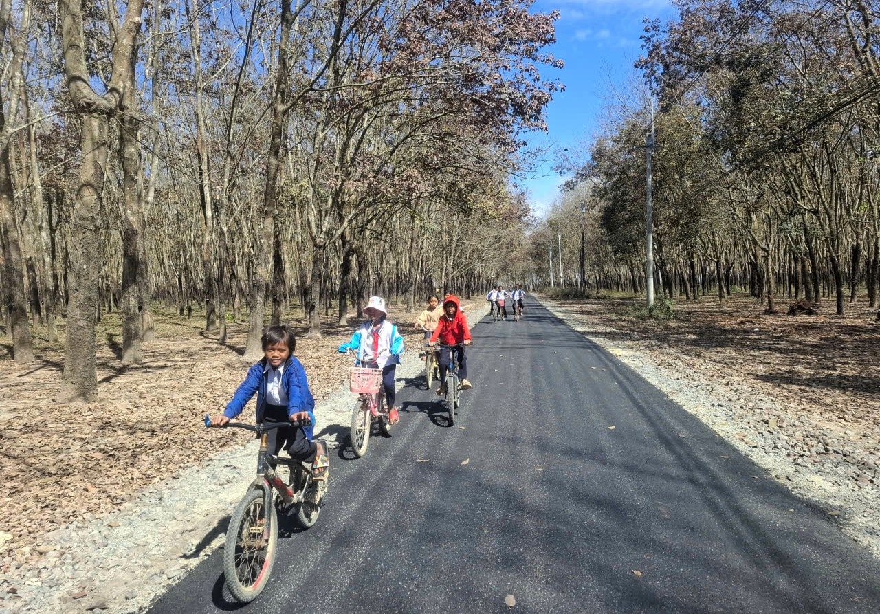 Em A Dũng (đi đầu) và các bạn phấn khởi đạp xe trên con đường mới để đến trường. (Ảnh: Ngọc Chí)