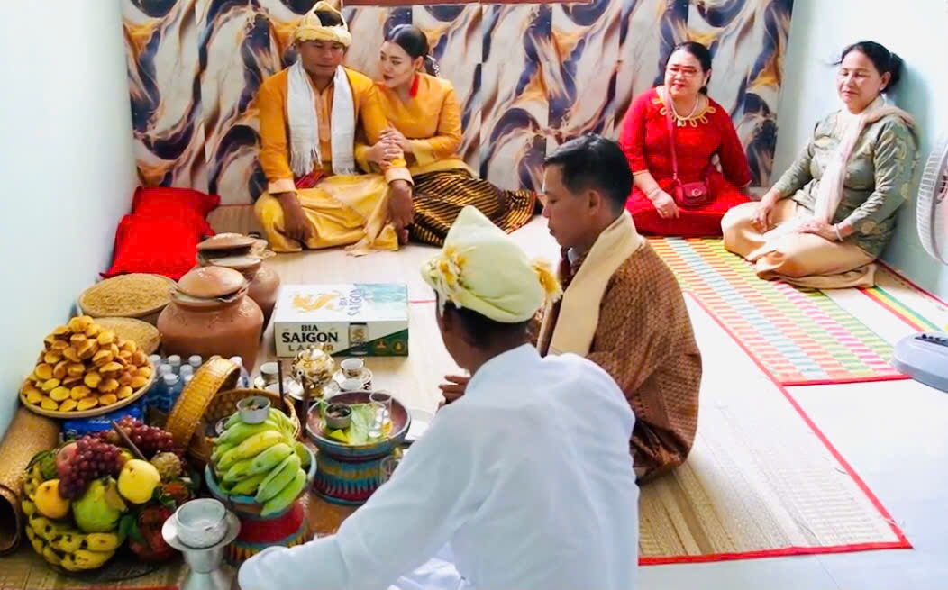 Cha đỡ đầu cô dâu đang hành lễ tác hợp cho cô dâu chú rễ tại phòng hoa chúc.