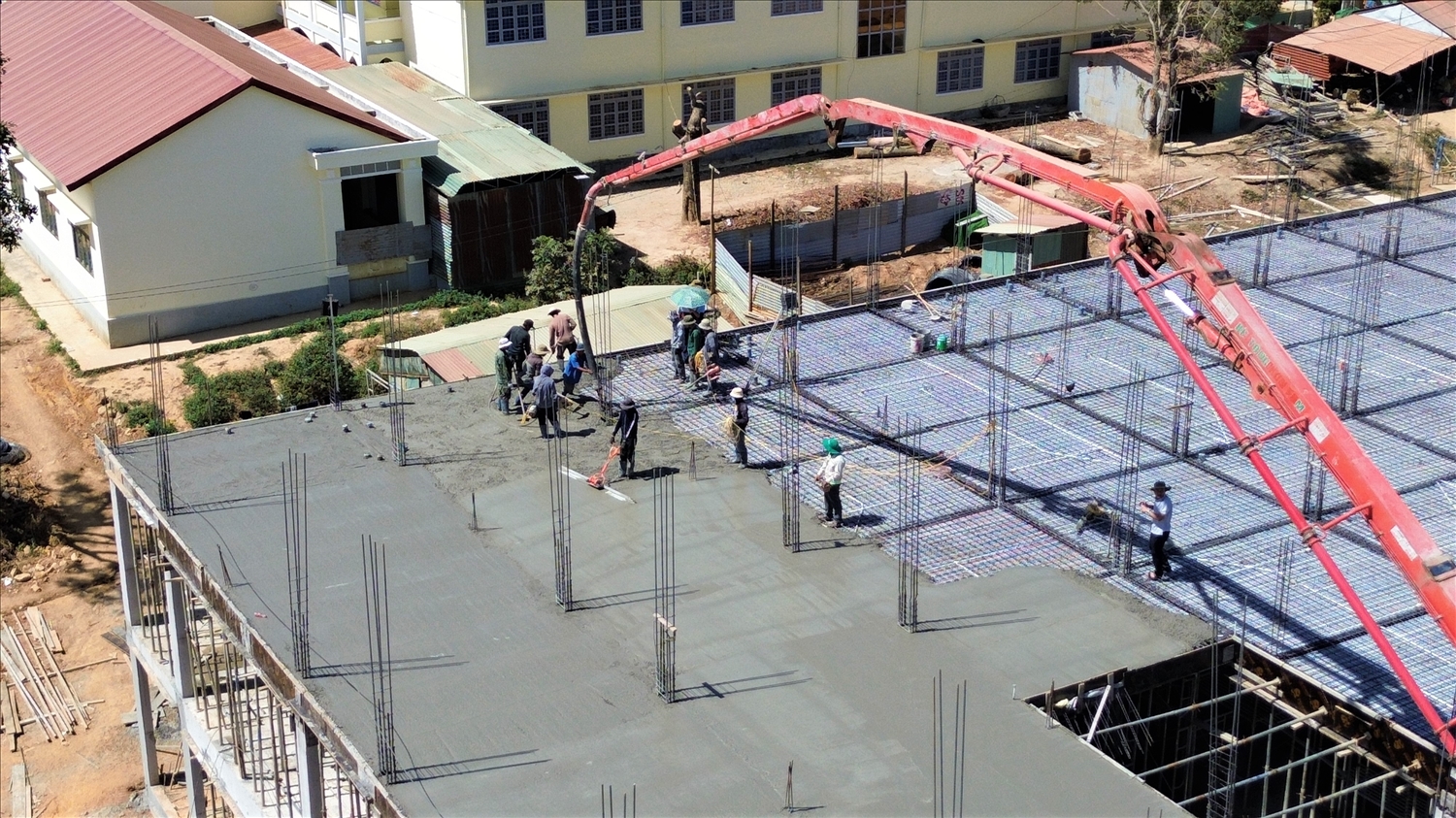 Các công nhân đang làm việc xuyên trưa, đổ bê tông sàn tầng 3 khu ký túc xá, Trường phổ thông nội trú liên cấp TH – THCS xã Rờ Kơi. (Ảnh: Ngọc Chí)