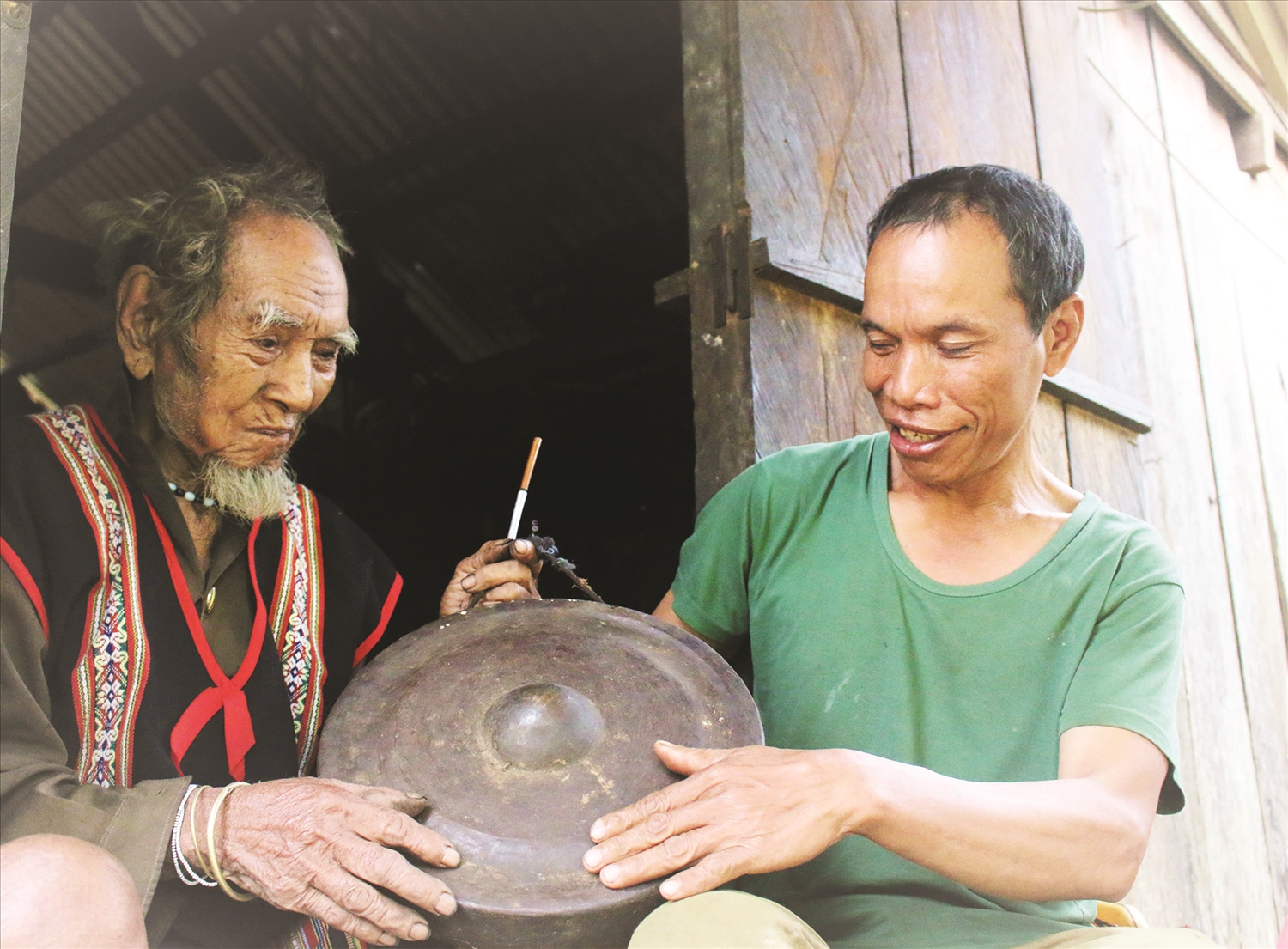 Nghệ nhân A Gíp trao đổi với con trai út là A Nam về cách bảo quản bộ cồng chiêng
