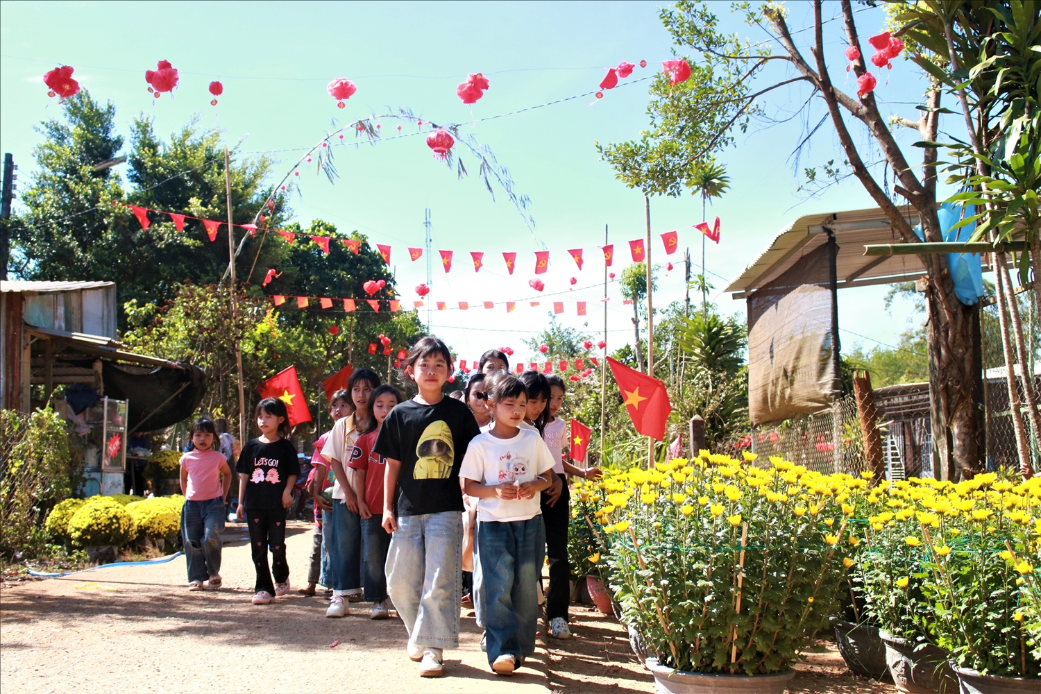 Trẻ em thôn Kon Gu 2, xã Ngọk Réo vui chơi trên những con đường thôn được trang trí rực rỡ cờ, hoa. (Ảnh: Ngọc Chí)