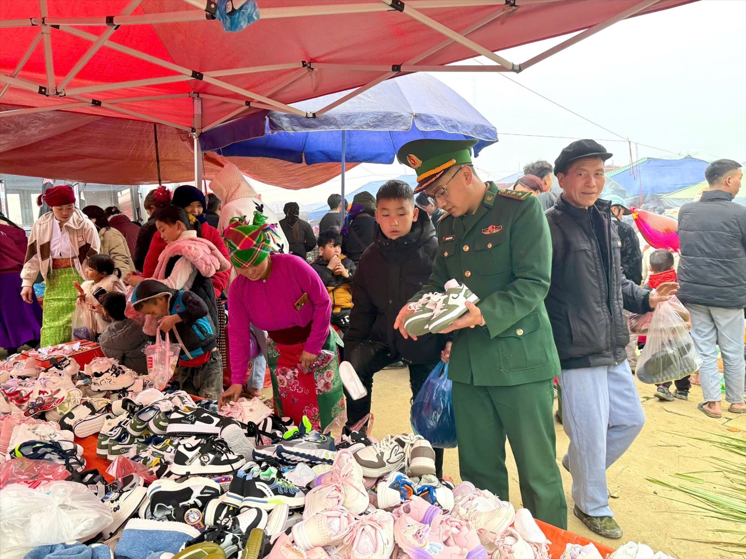 Cán bộ, chiến sĩ đưa con nuôi của đơn vị đi chợ mua giầy, dép, quần áo mới.