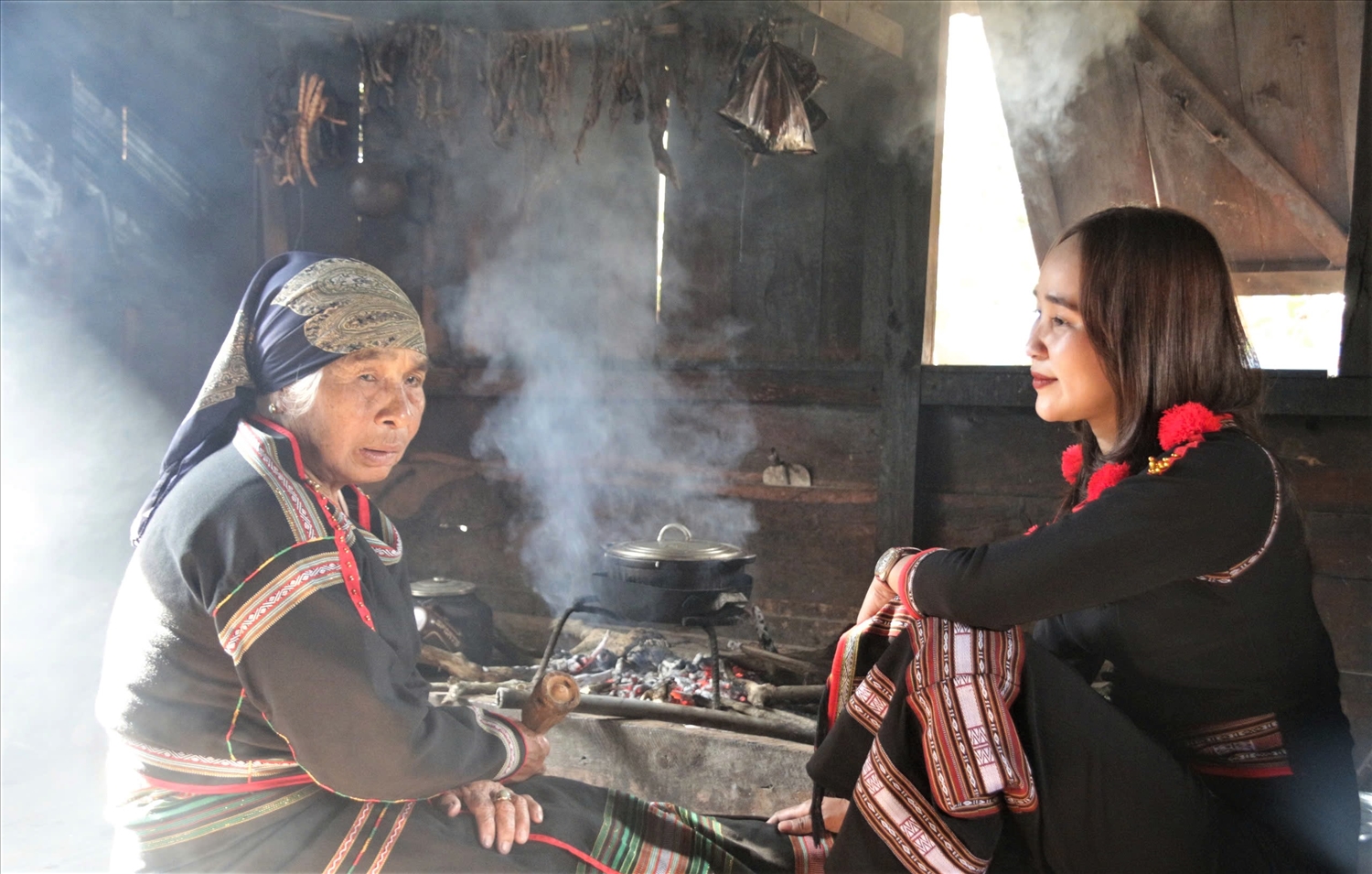 Ngồi bên bếp lửa bà H’Loi Byă kể cho con cháu nghe những câu chuyện xưa, cách chế biến món ăn truyền thống