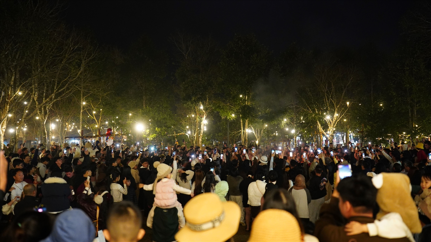 Du khách dùng điện thoại ghi lại khoảnh khắc tại đêm hội cồng chiêng tại không gian Chợ phiên Măng Đen