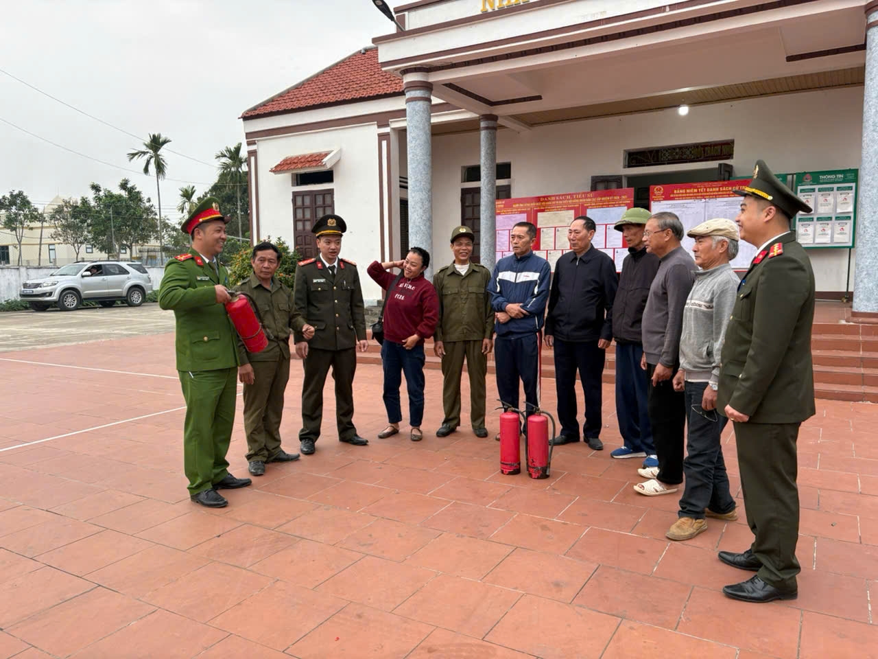 Công an xã Hồ Vương hướng dẫn người dân sử dụng bình chữa cháy tại điểm niêm yết danh sách bầu cử