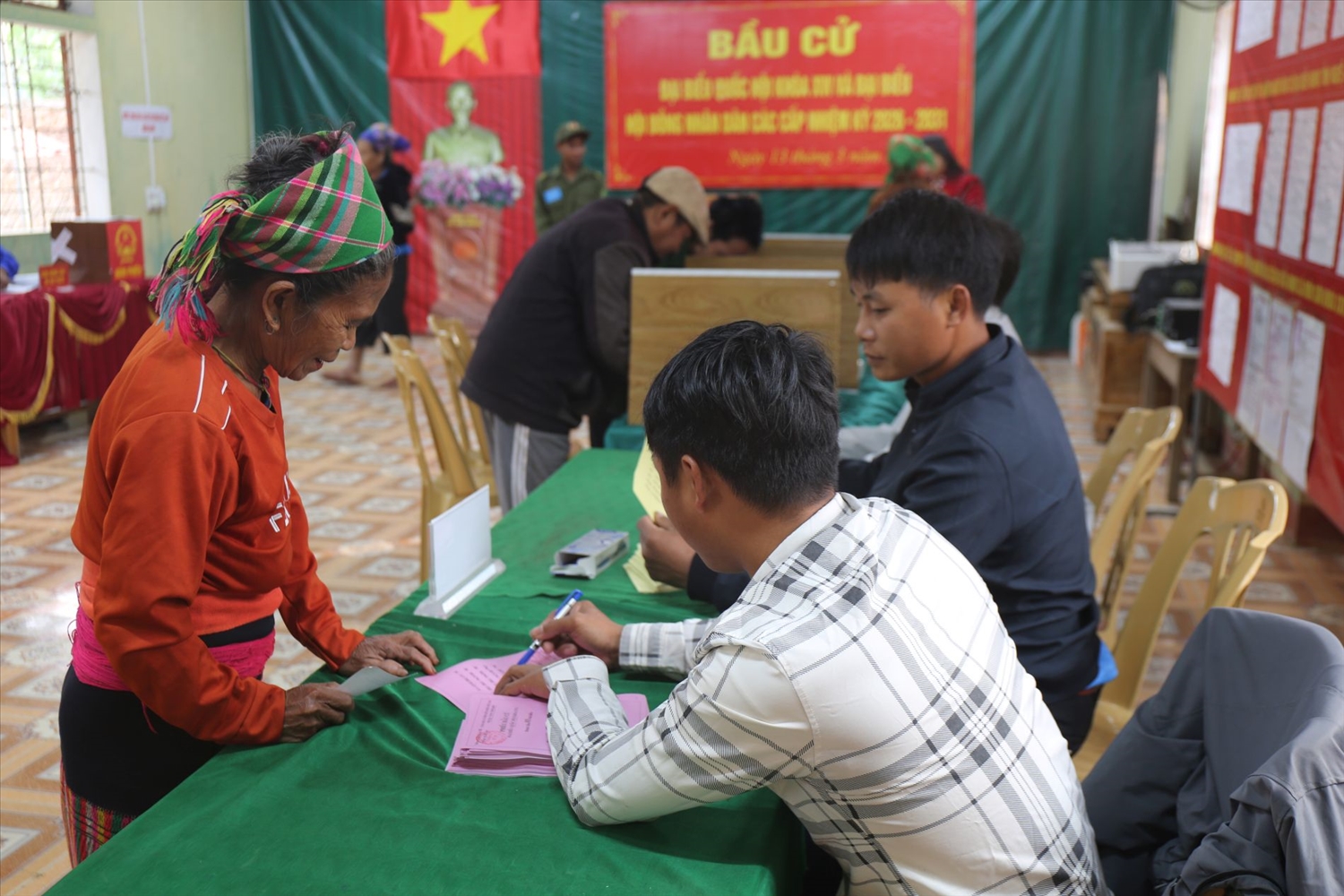 Người dân Đan Lai được cán bộ tổ bầu cử hướng dẫn tỉ mỉ cách viết phiếu bầu - Ảnh: Thanh Hải