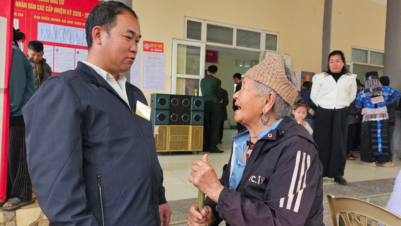 Trưởng bản Kéo Hươn xã Nhi Sơn trao đổi, hướng dẫn cử tri cao tuổi trước khi vào khu vực bỏ phiếu.