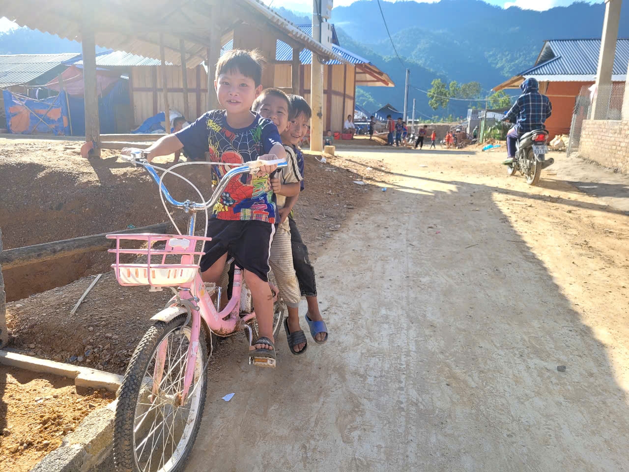 Trẻ em vui đùa trước những ngôi nhà mới tại khu tái định cư, niềm vui giản dị trên miền đất bình yên.