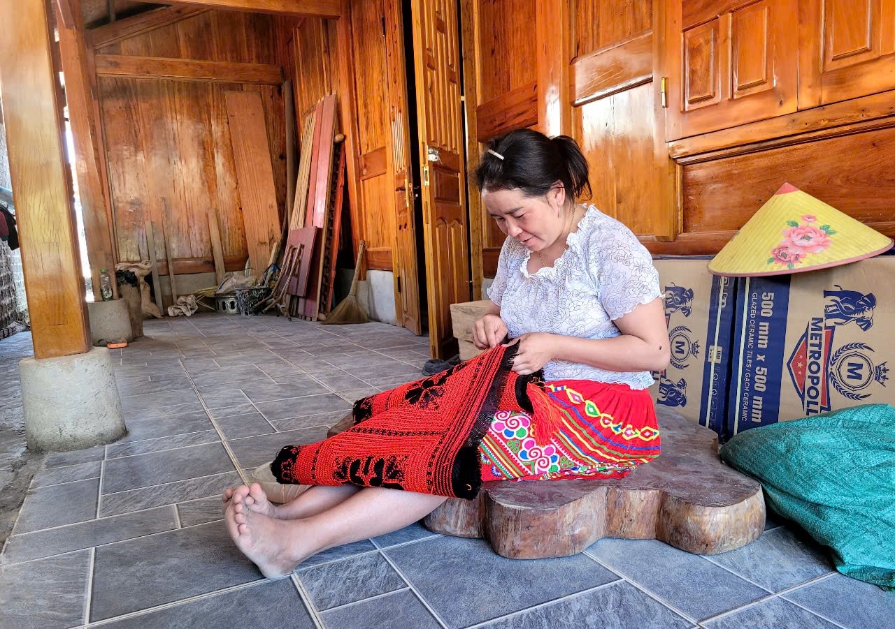 Phụ nữ dân tộc Mông tại khu tái định cư bản Ún, xã Mường Lý tranh thủ thêu thùa trang phục truyền thống khi nông nhàn