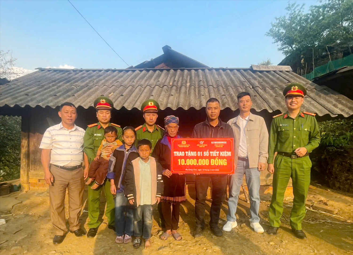 Bà nội và 3 cháu nhỏ nhận cuốn sổ tiết kiệm trị giá 10 triệu đồng từ tay các chiến sĩ Công an và nhà tài trợ. 