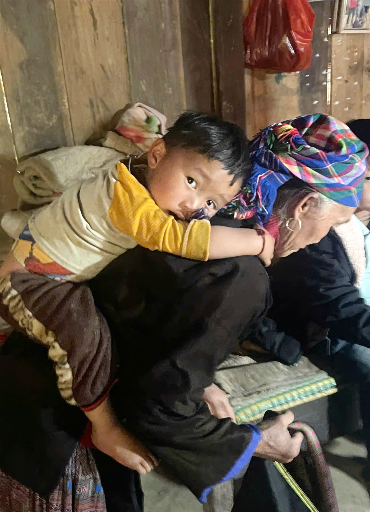 Gương mặt ngây thơ nhưng đượm buồn của bé Giàng A Tông trên lưng bà nội. Bé vẫn chưa cảm nhận hết nỗi đau vắng bóng cả cha lẫn mẹ