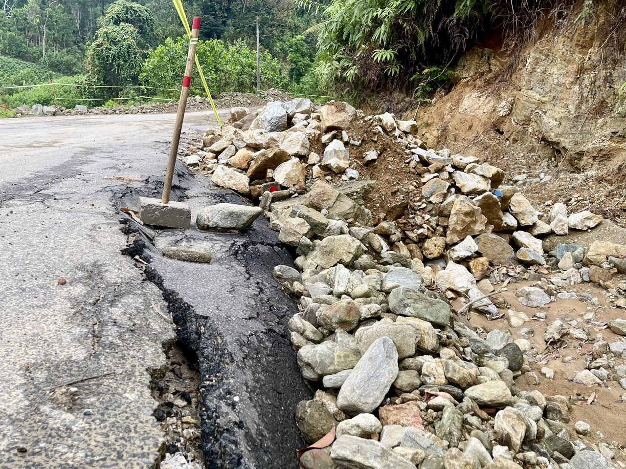 Mặt đường đoạn qua xã Trà Tập bị hư hỏng nặng, đất đá tiếp tục tràn xuống. (Ảnh Huy Trường)