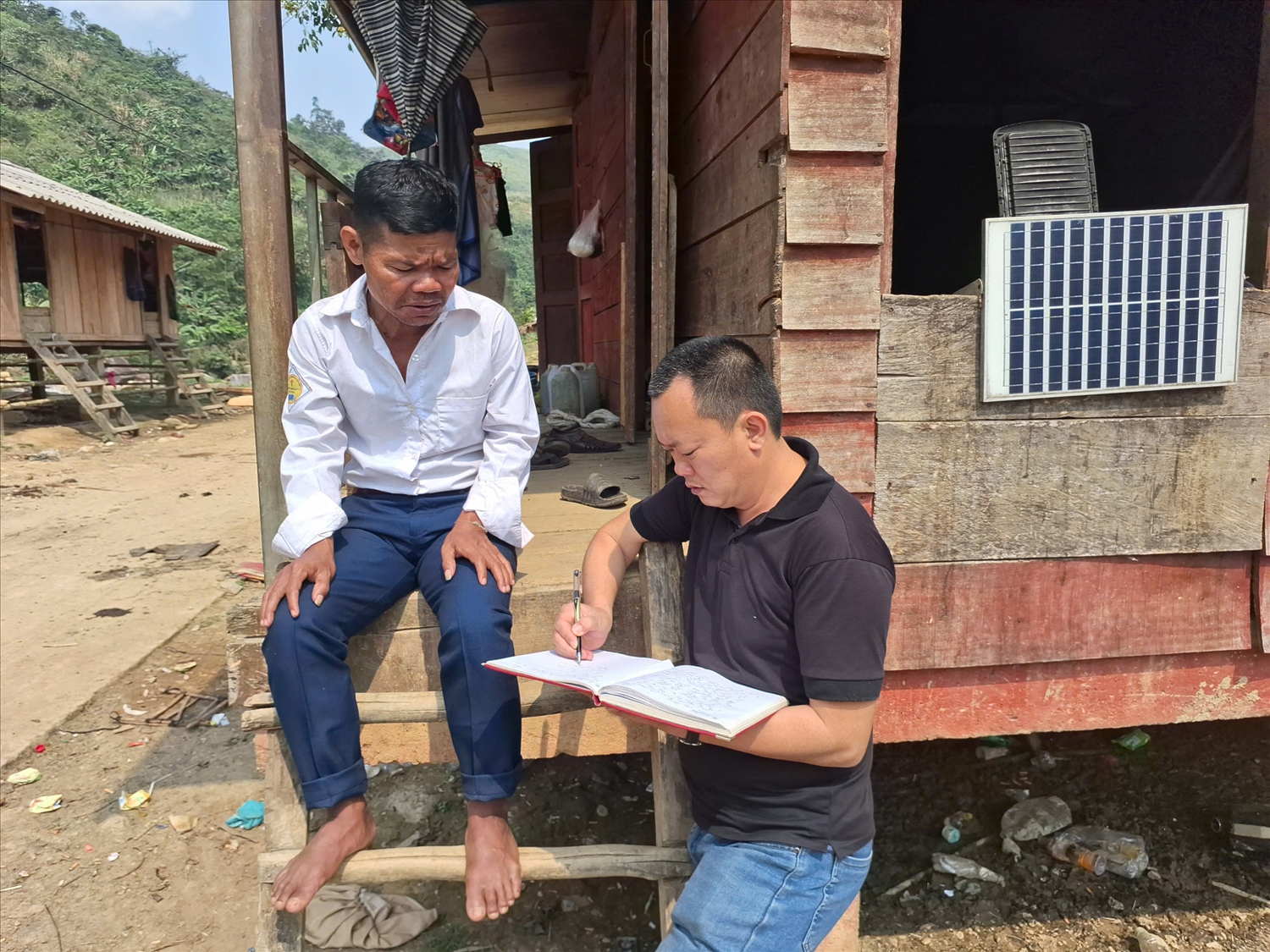 Trưởng bản Hồ Kiên (trái) vui mừng chia sẻ: Có đường, có điện về, bà con đi lại và sinh hoạt tiện lợi hơn