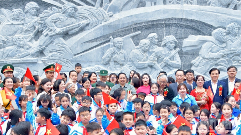 Thủ tướng Phạm Minh Chính với các cháu học sinh tại khu vực bức phù điêu trong Khu di tích Trung tâm đề kháng Him Lam. (Ảnh: THANH GIANG)