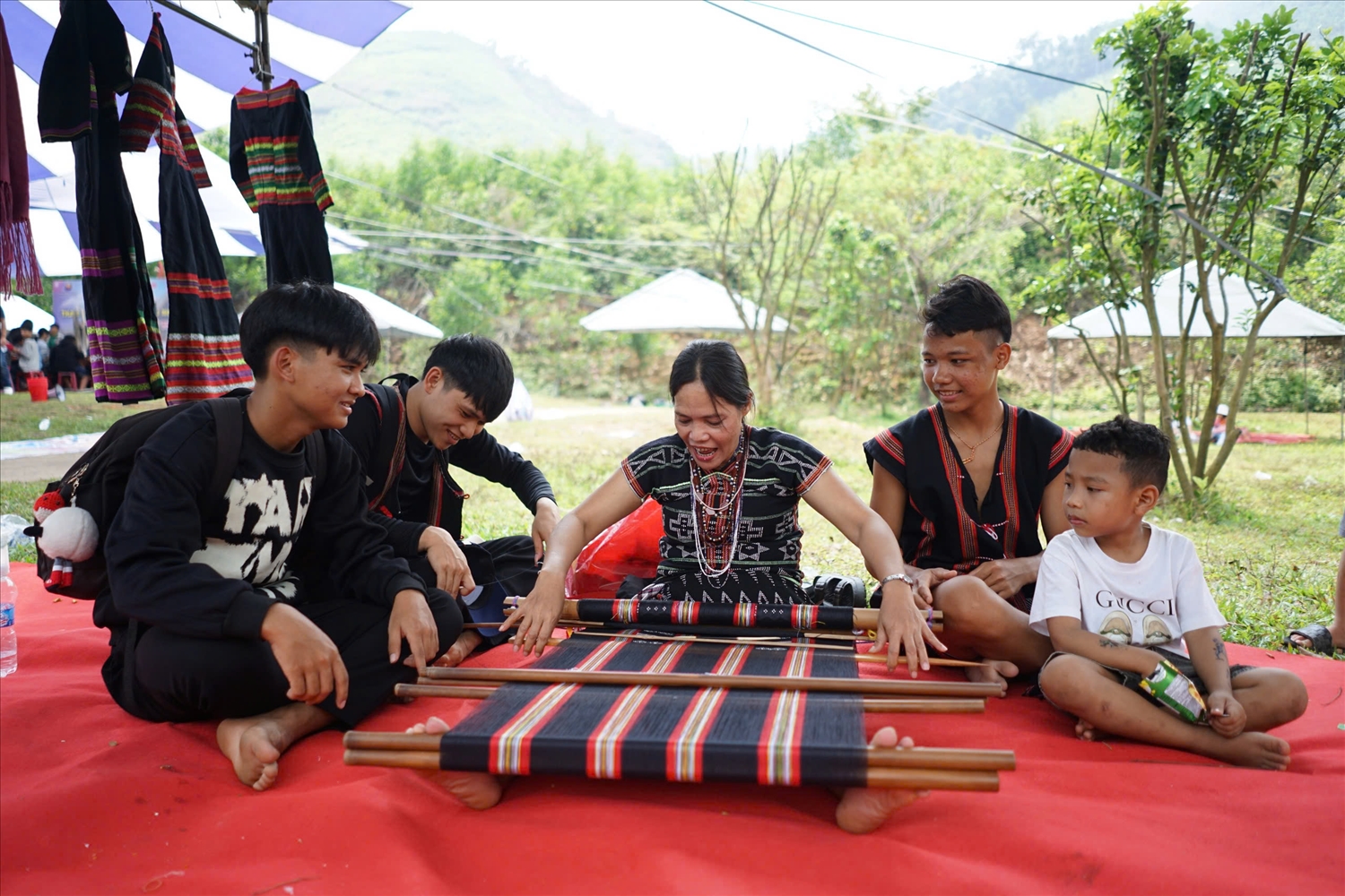 Thành viên Tổ dệt thổ cẩm làng Dhroồng giới thiệu phương pháp dệt thổ cẩm của đồng bào Cơ Tu với du khách. (Ảnh XS)