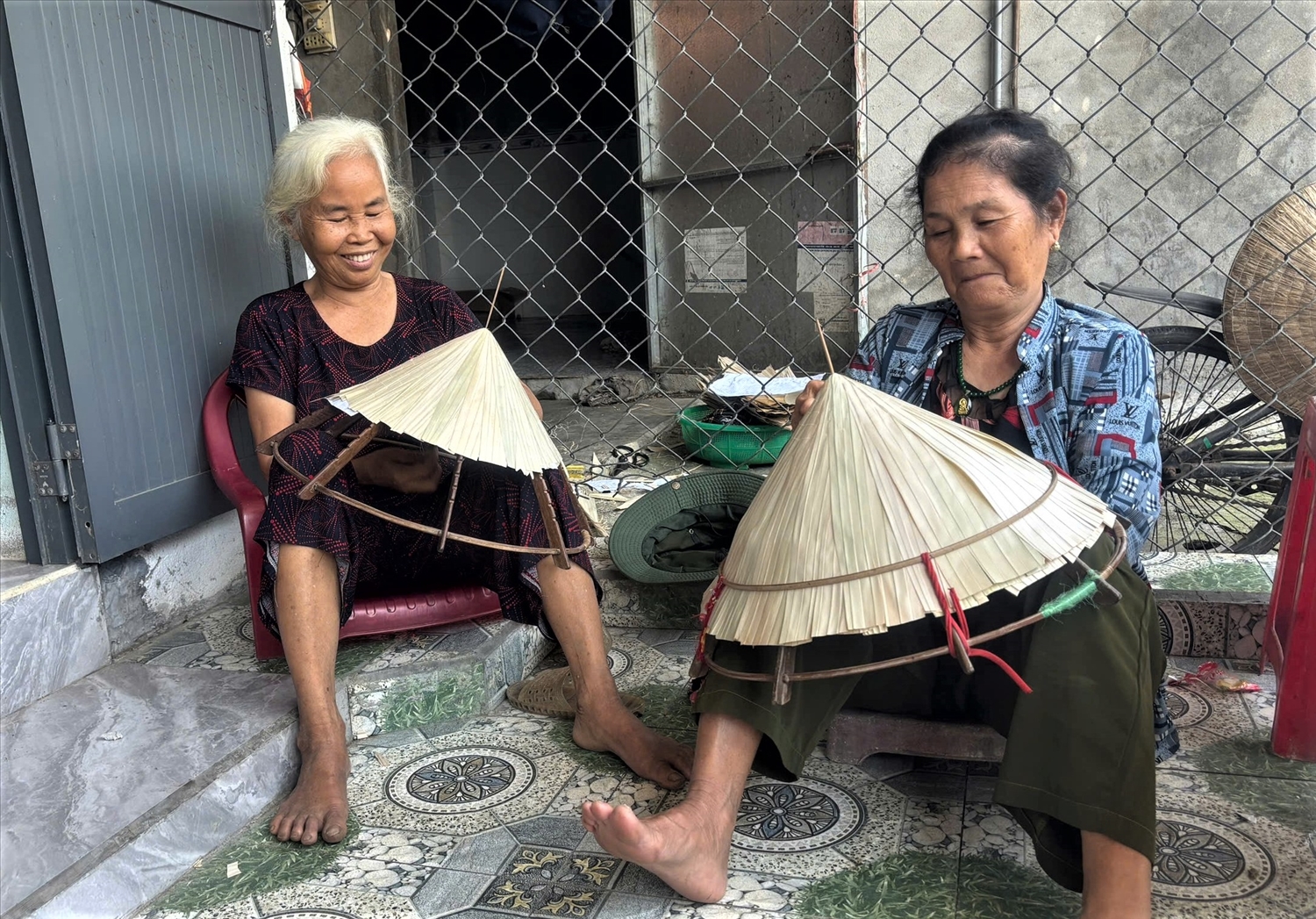 Những người phụ nữ lớn tuổi ở Hòa Thịnh tỉ mỉ khâu từng mũi kim, sợi cước để hoàn thành chiếc nón lá.