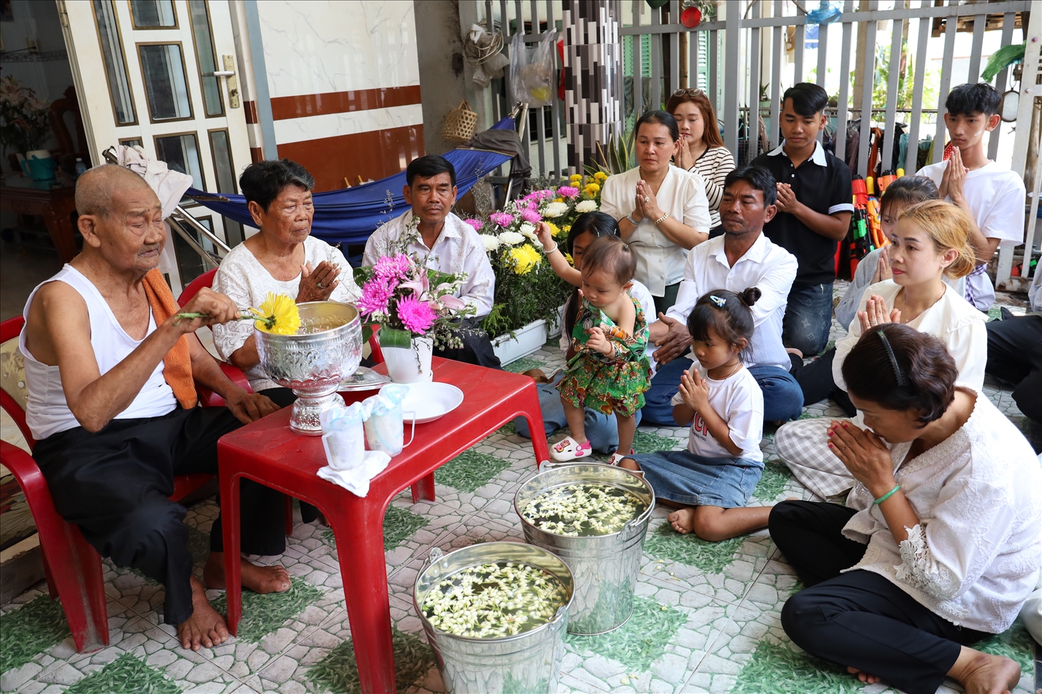 Ông Lý Tiêng (88 tuổi) và bà Dương Thị Phanh (83 tuổi) ngồi trên chiếc ghế đặt trước nhà ở phường Ô Môn, TP. Cần Thơ, lần lượt gửi lời chúc sức khỏe, bình an và phát đạt đến hơn 20 người con và cháu của mình.