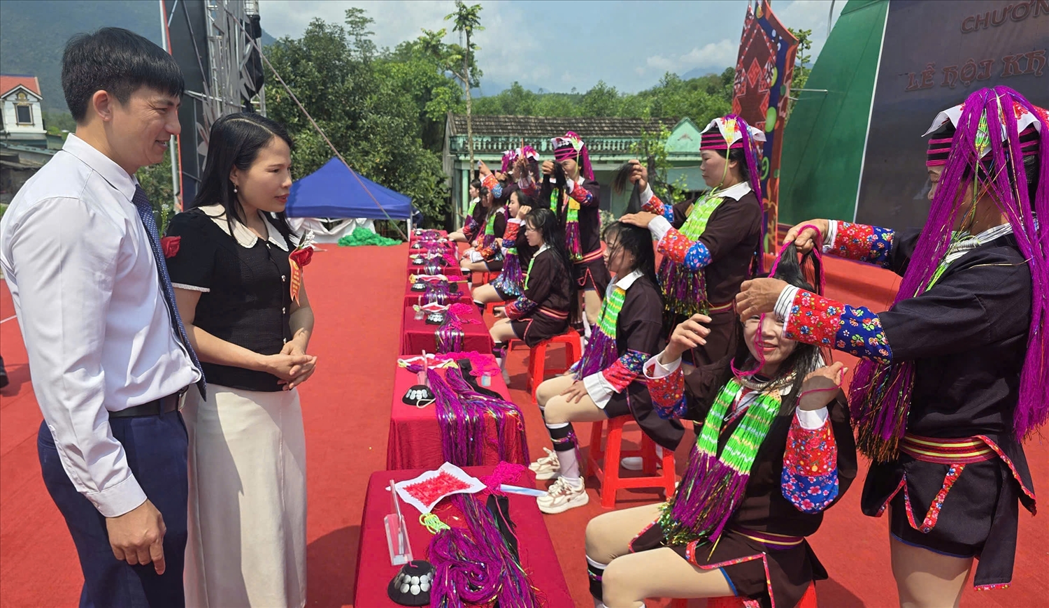 Phó Giám đốc Sở Dân tộc và Tôn giáo tỉnh Quảng Ninh Ân Thị Thìn cùng lãnh đạo xã Đường Hoa theo dõi phần thi vấn tóc – nét văn hóa đặc sắc của đồng bào vùng cao đang được bảo tồn và phát huy gắn với phát triển du lịch cộng đồng. Ảnh: Mỹ Dung