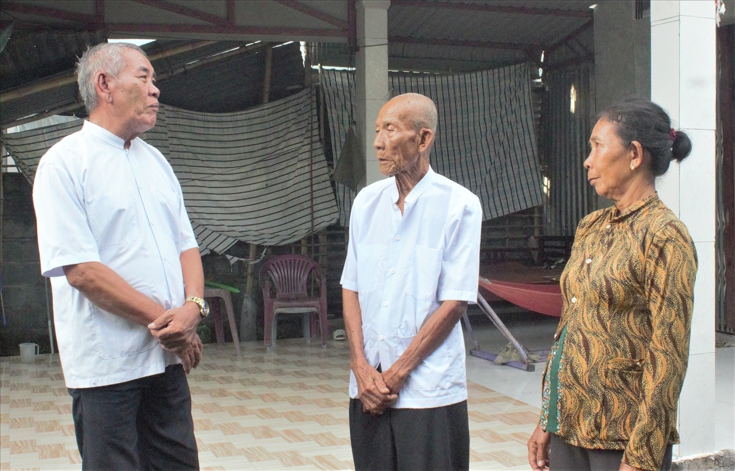 Ông Chau Siêm (bên trái) đến tuyên truyền, vận động người dân địa phương chấp hành tốt chủ trương, đường lối của Đảng, chính sách, pháp luật của Nhà nước. (Ảnh: Tào Đạt)