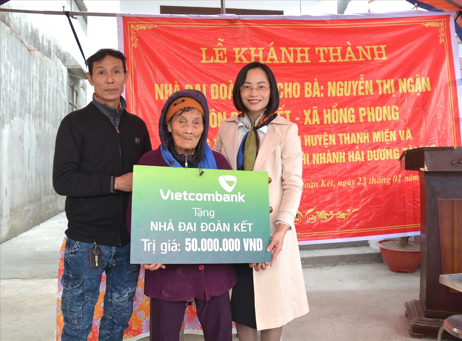 Bà Phạm Minh Đào - Phó Giám đốc Vietcombank Hải Dương (ngoài cùng bên phải) trao biển tặng nhà đại đoàn kết cho gia đình bà Nguyễn Thị Ngận, hộ nghèo thuộc huyện Thanh Miện, tỉnh Hải Dương
