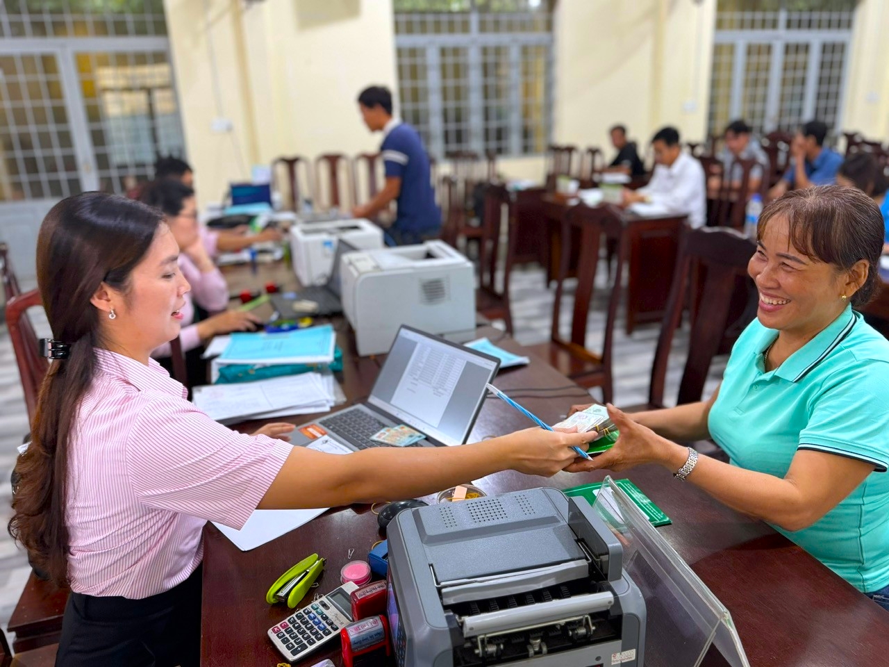 Người dân vui mừng phấn khởi khi nhận tiền vay từ cán bộ (tại Điểm giao dịch xã Lộc Phú, huyện Lộc Ninh), để đầu tư SXKD