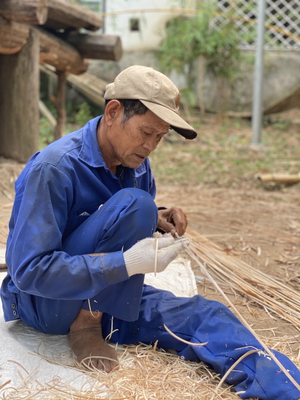 Bác Siu Kuai (sinh năm 1949), người nhiều tuổi nhất nhóm thợ đang vót mây chuẩn bị cho công đoạn buộc cỏ tranh và sàn, vách nhà